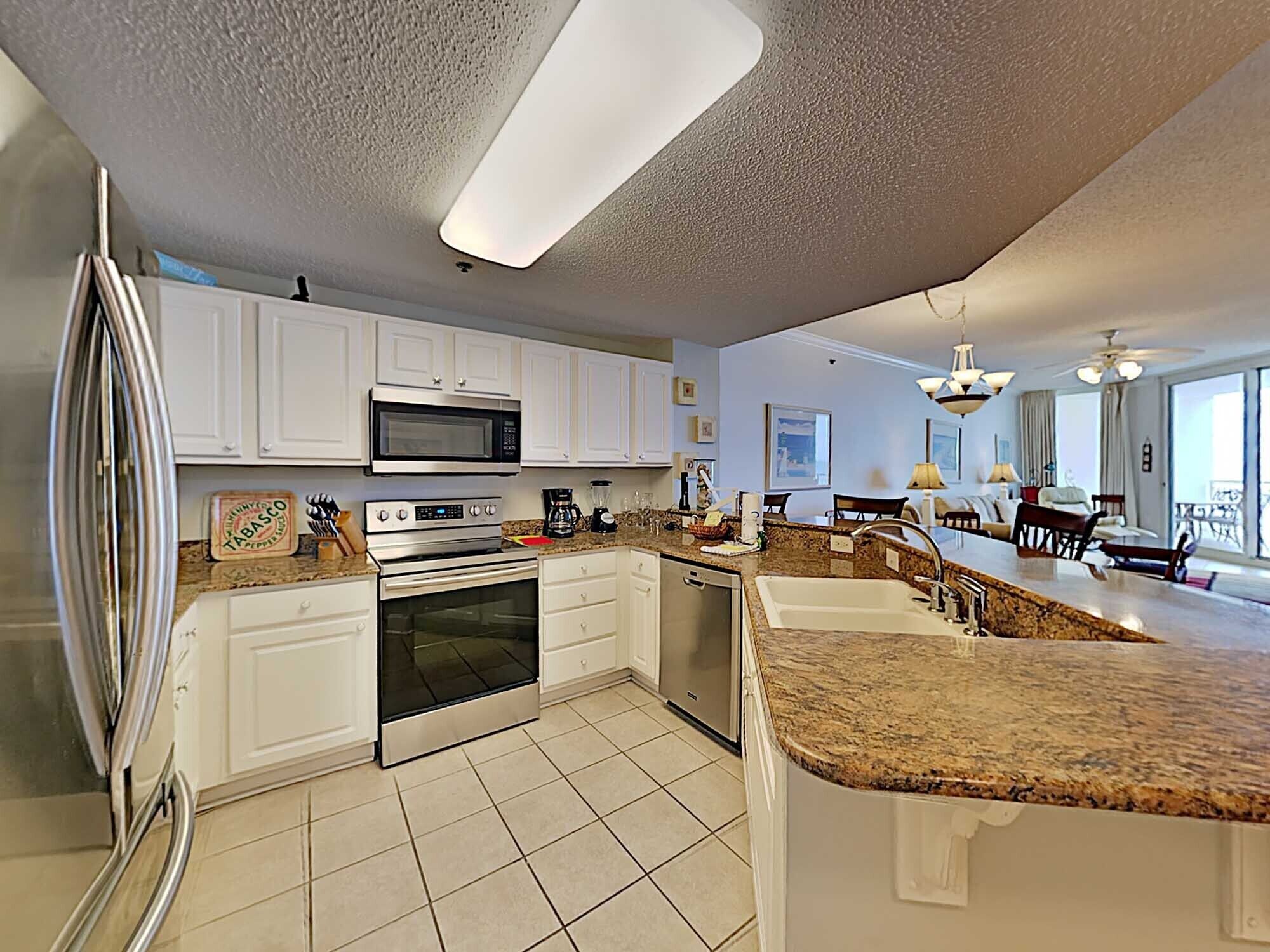 A modern kitchen with white cabinets, stainless steel appliances, and a granite countertop.