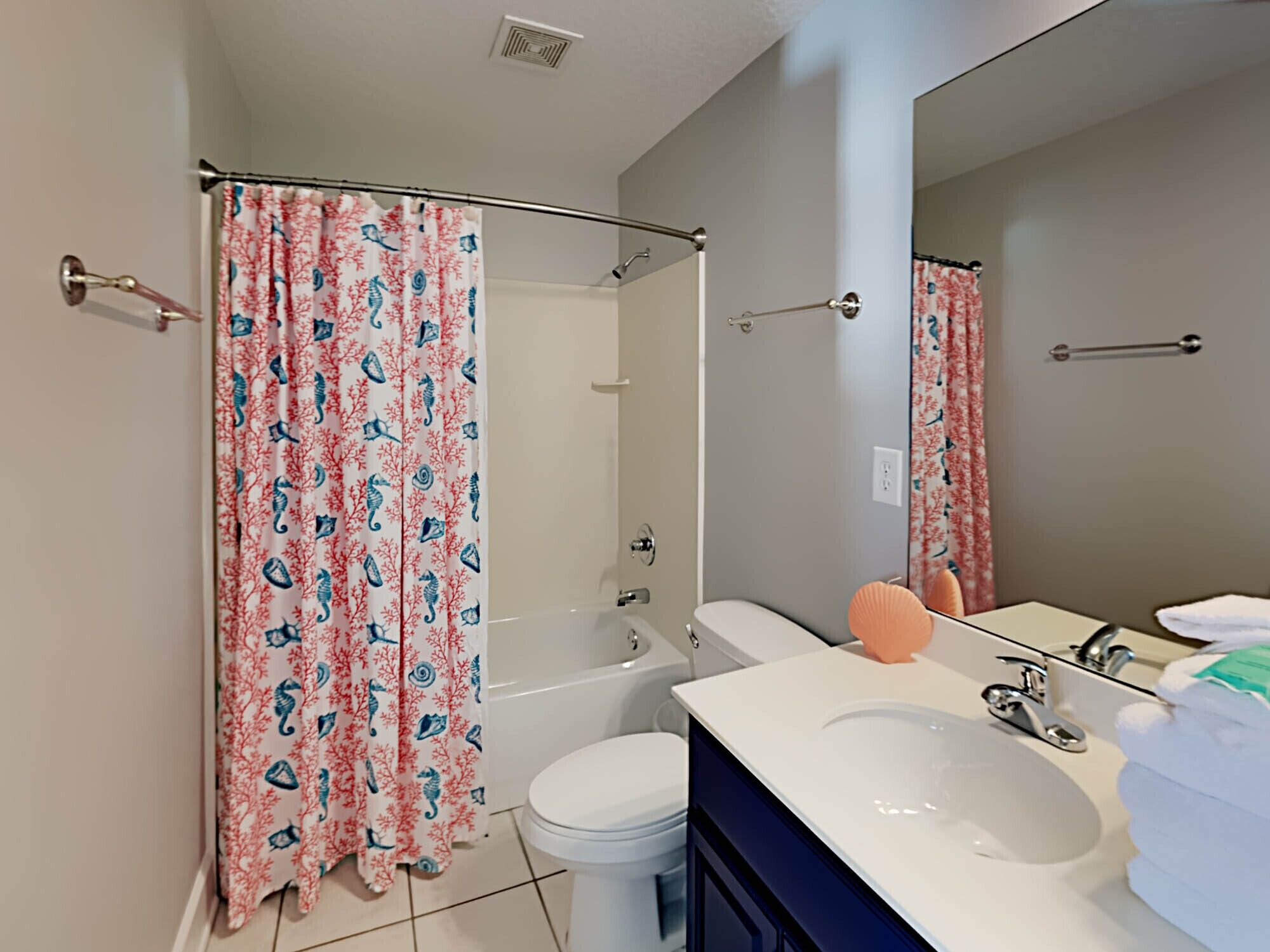 A bathroom with a shower, toilet, sink, and a large mirror.