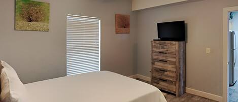 A bedroom with a bed, a ceiling fan, a dresser, and a television.
