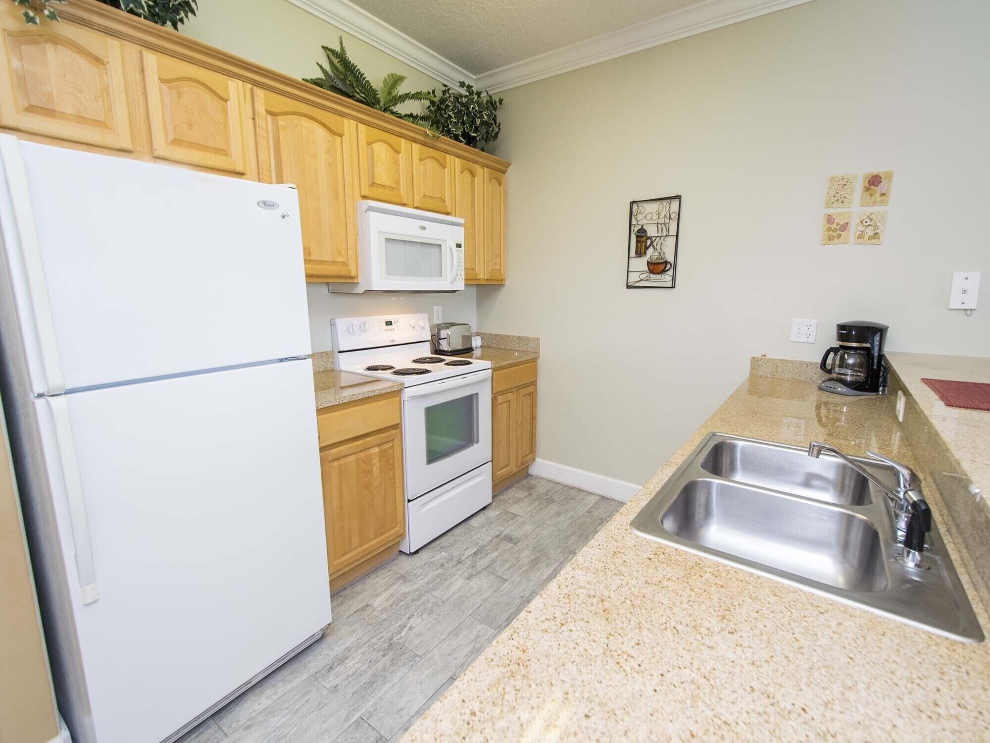 A kitchen with wooden cabinets, a white refrigerator, a microwave, a stove, and a sink.