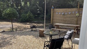 Un patio al aire libre con una mesa redonda y sillas, rodeado de grava y una valla de madera.