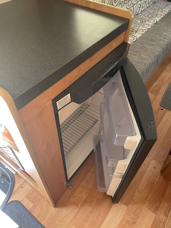 A compact kitchen area with a built-in refrigerator and a wooden countertop.