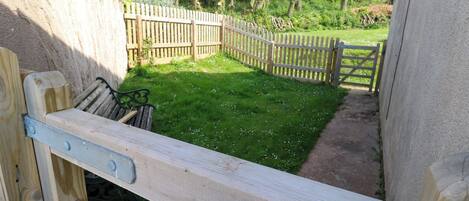 A wooden bench in a garden area with a wooden fence and a gate.