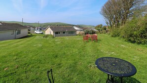 A grassy backyard with a trampoline, a red playset, and a house in the background. - Jasper's Corner (Kingsbridge)