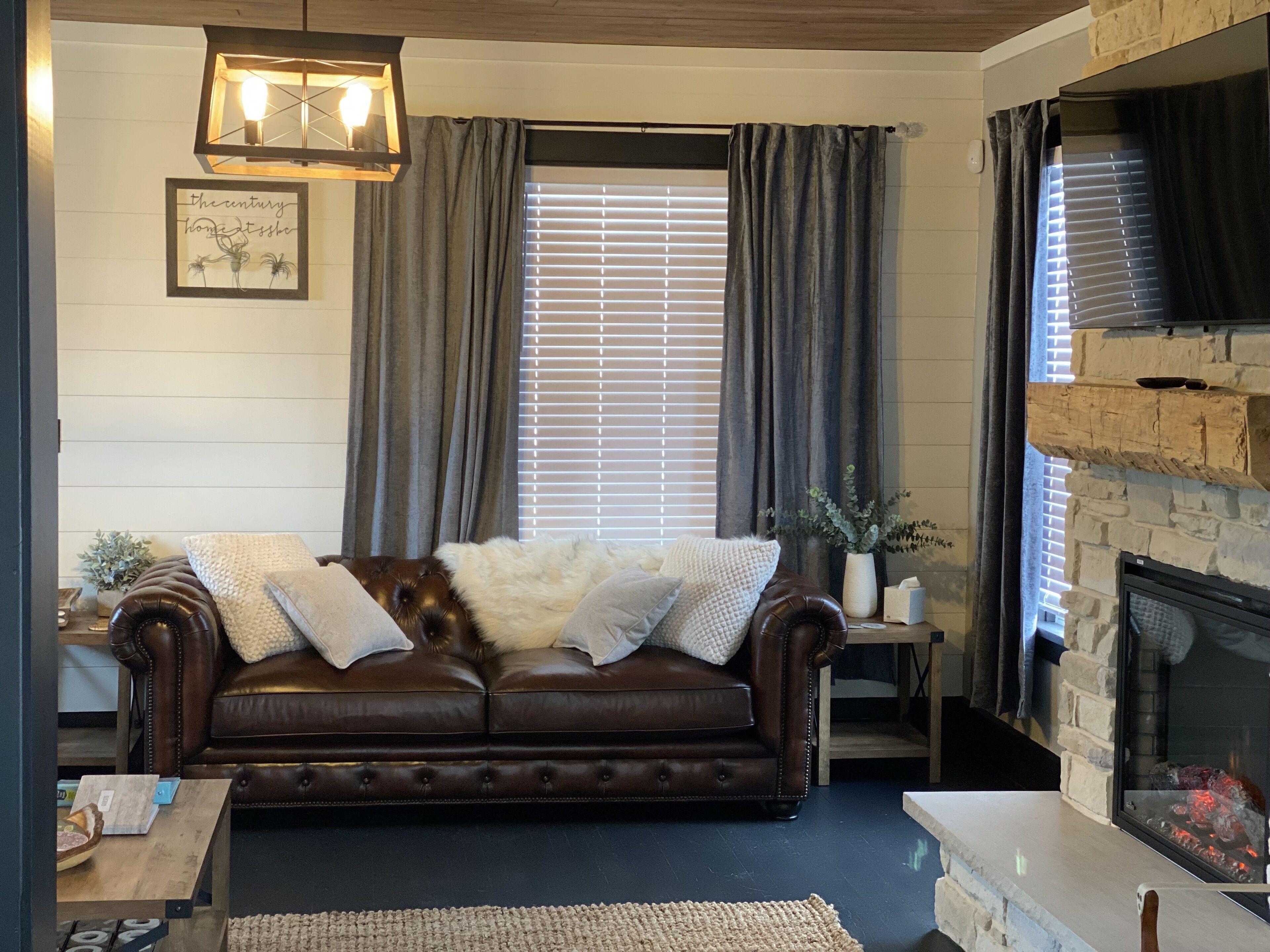 Een gezellige woonkamer met een leren bank, een open haard en een raam met gordijnen.
