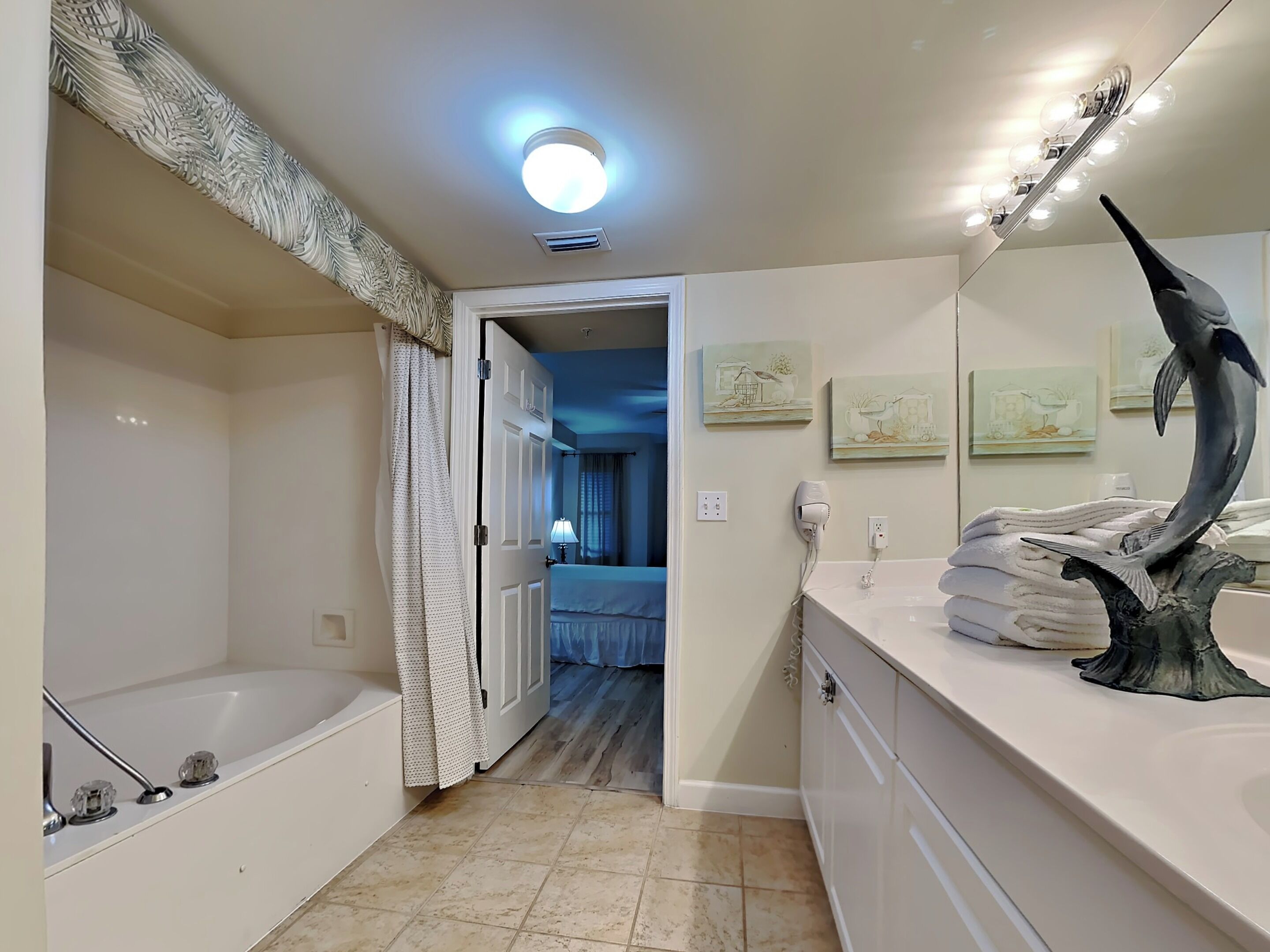 A modern bathroom with a bathtub, a large mirror, and artwork on the walls.