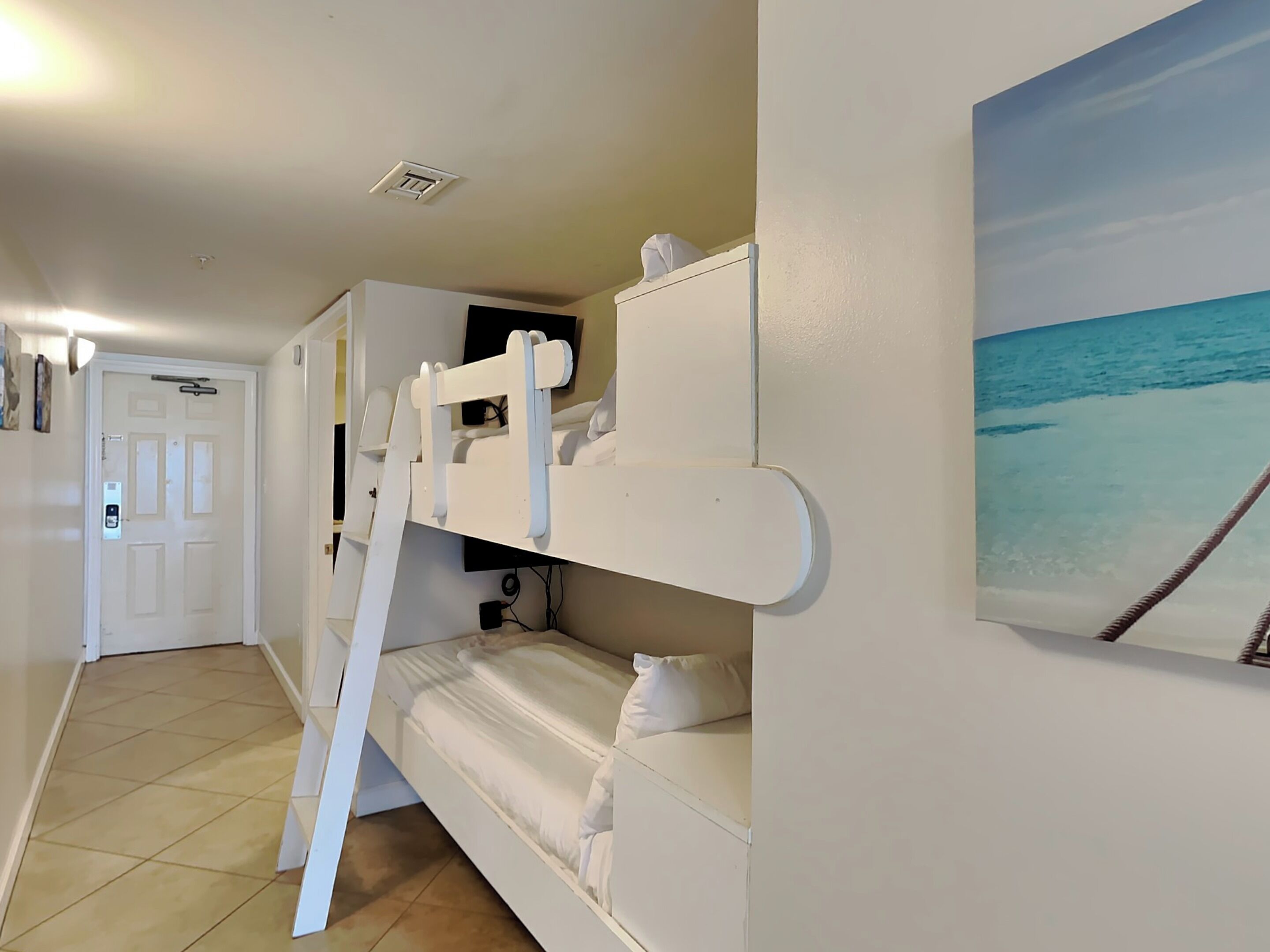 A bunk bed room with a painting of a beach on the wall.