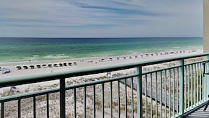 Un balcon donnant sur une plage, avec des parasols et des gens.