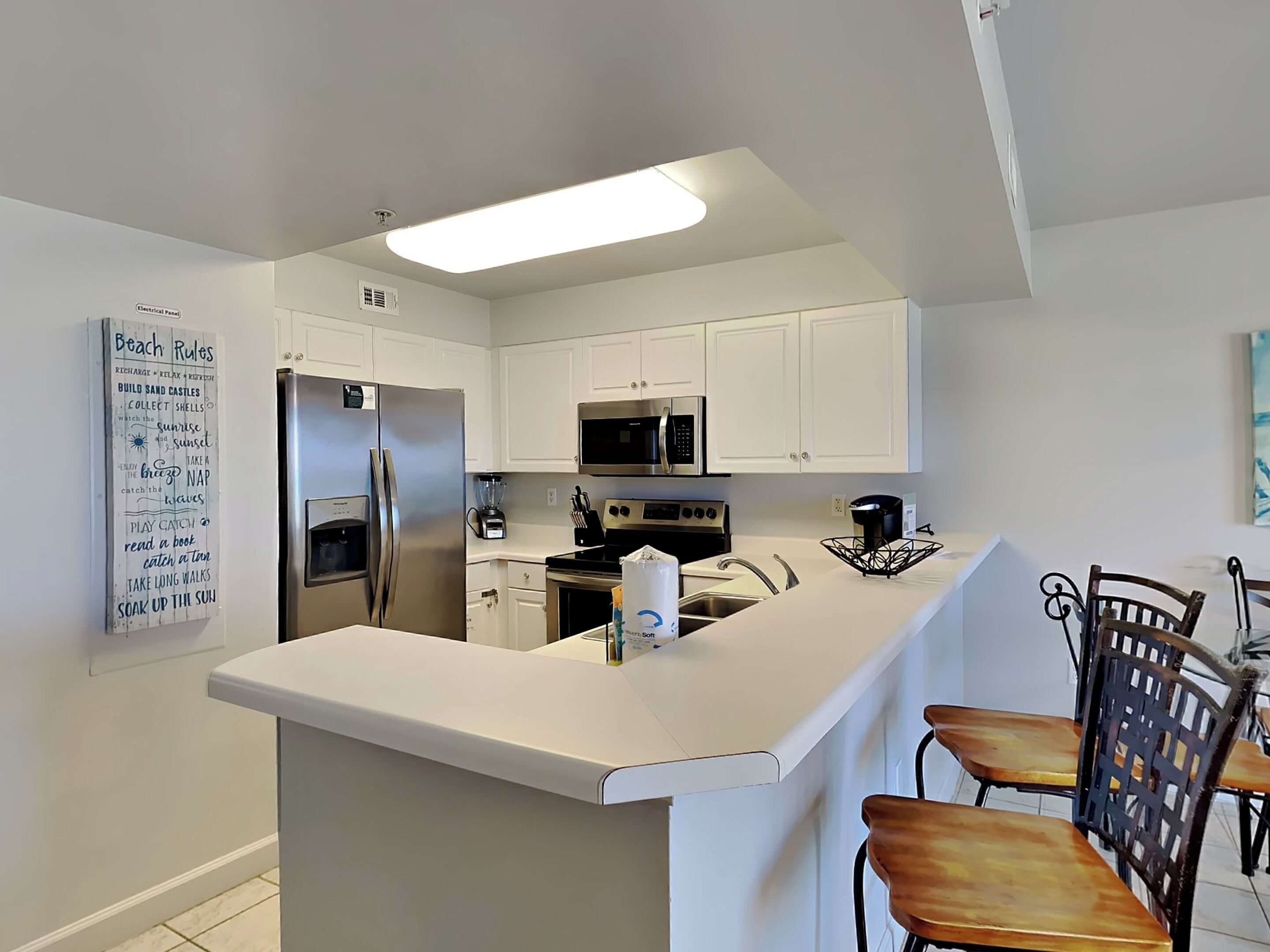 A modern kitchen with white cabinets, stainless steel appliances, and a central island.