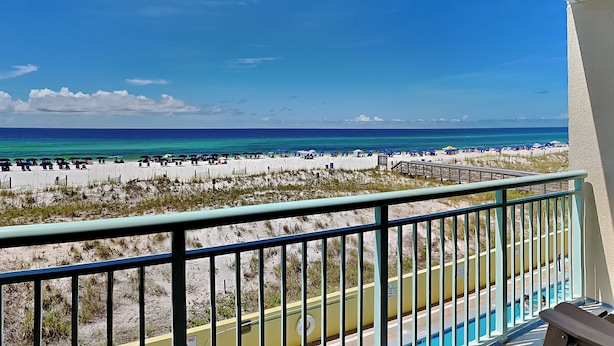 Un balcon avec vue sur une plage et une piscine.