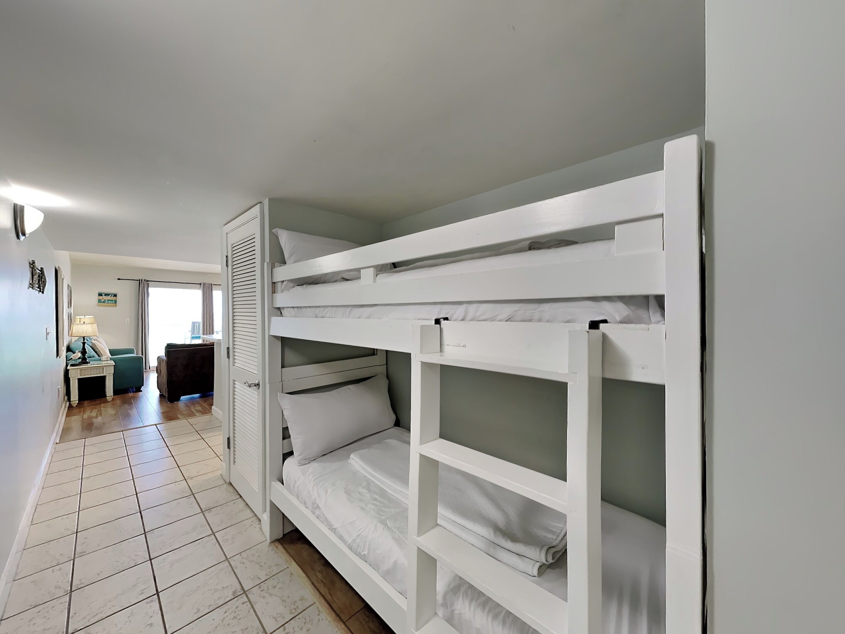 A room with bunk beds, a desk, a chair, and a lamp.