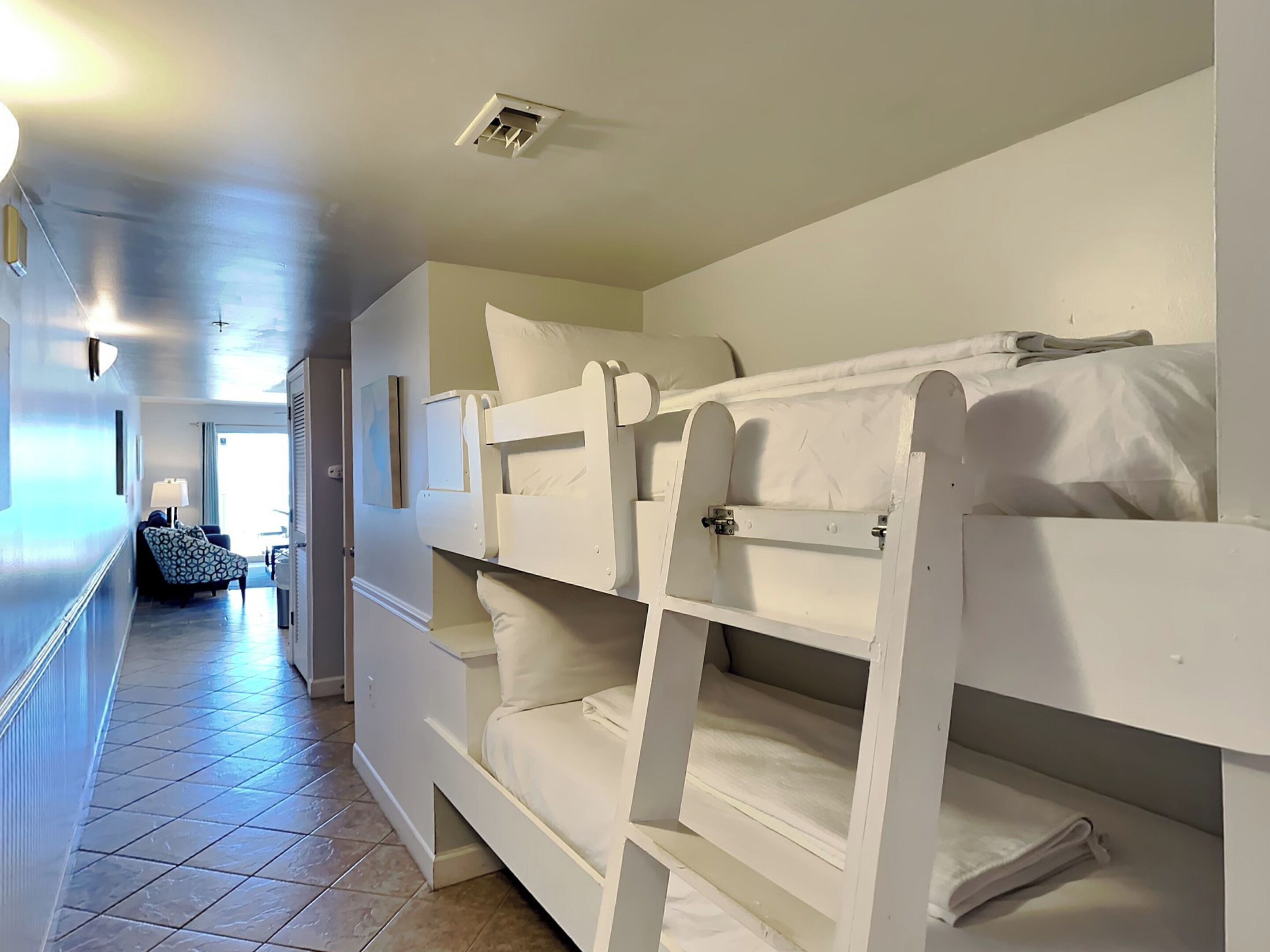 A hotel room with bunk beds, a hallway, and a bathroom.