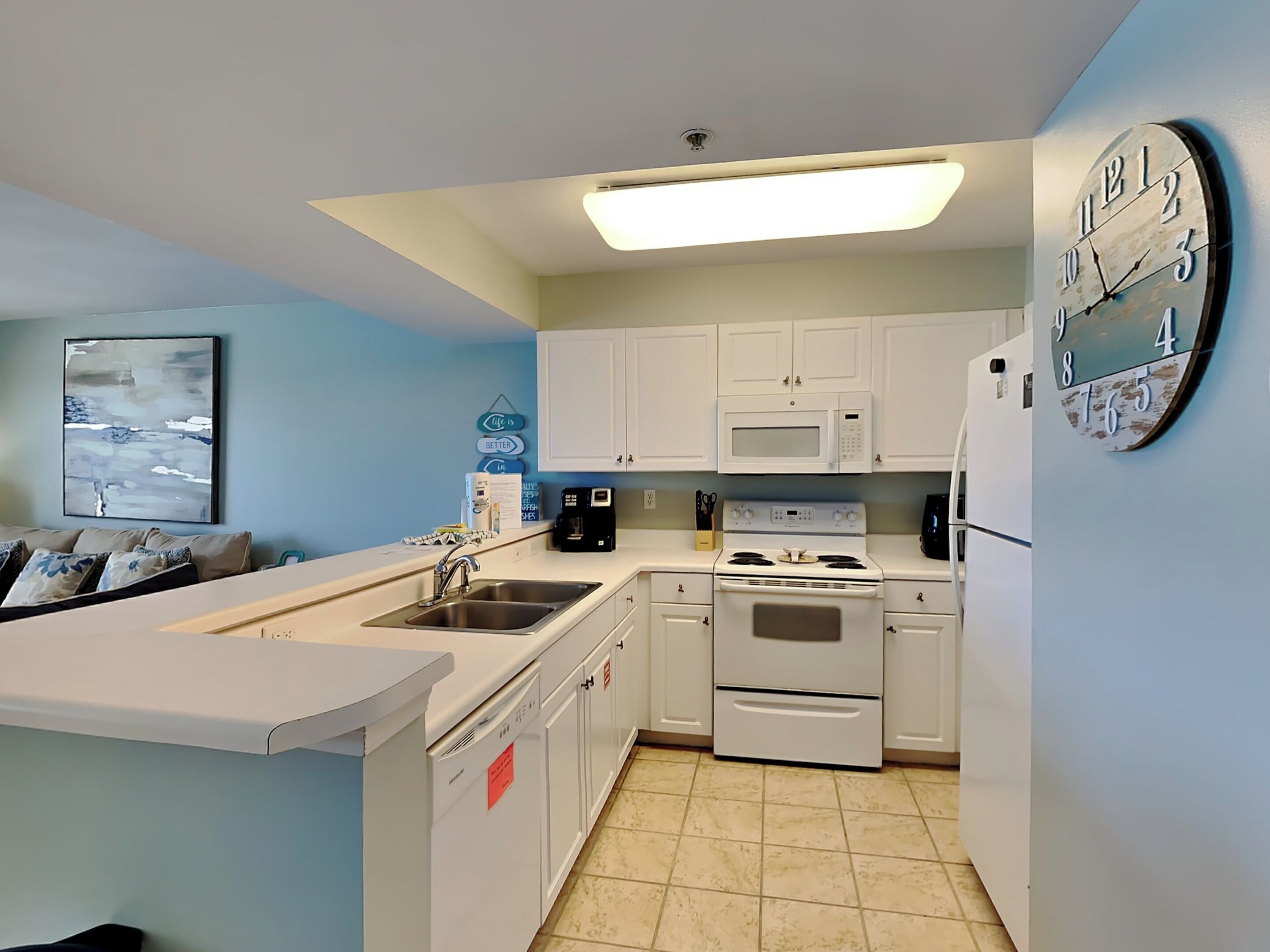 A compact kitchen with white cabinets, a built-in oven, a microwave, and a sink.