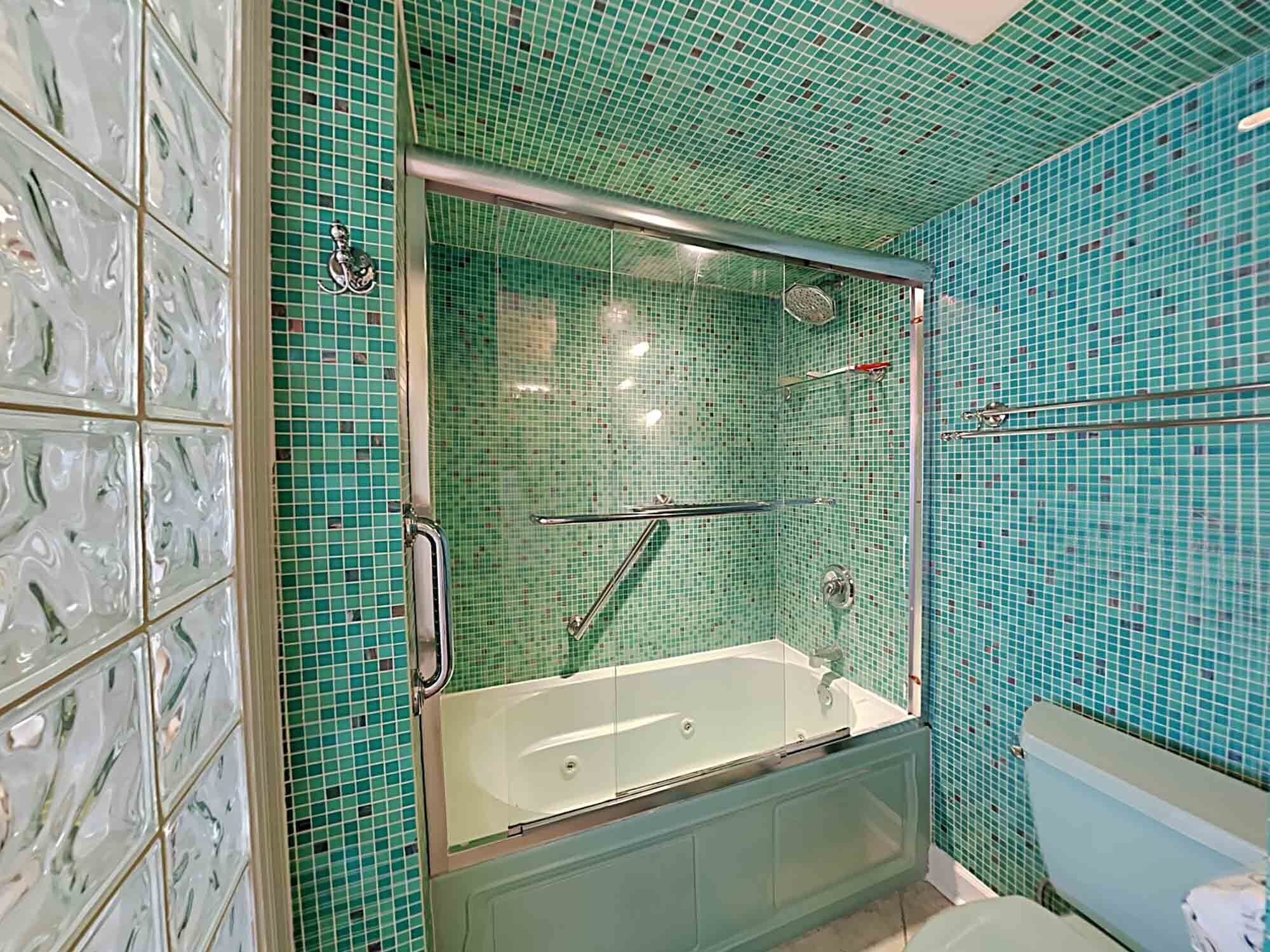 A bathroom with a glass-enclosed shower, a bathtub, and a toilet.