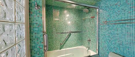 A bathroom with a glass-enclosed shower, a bathtub, and a toilet.
