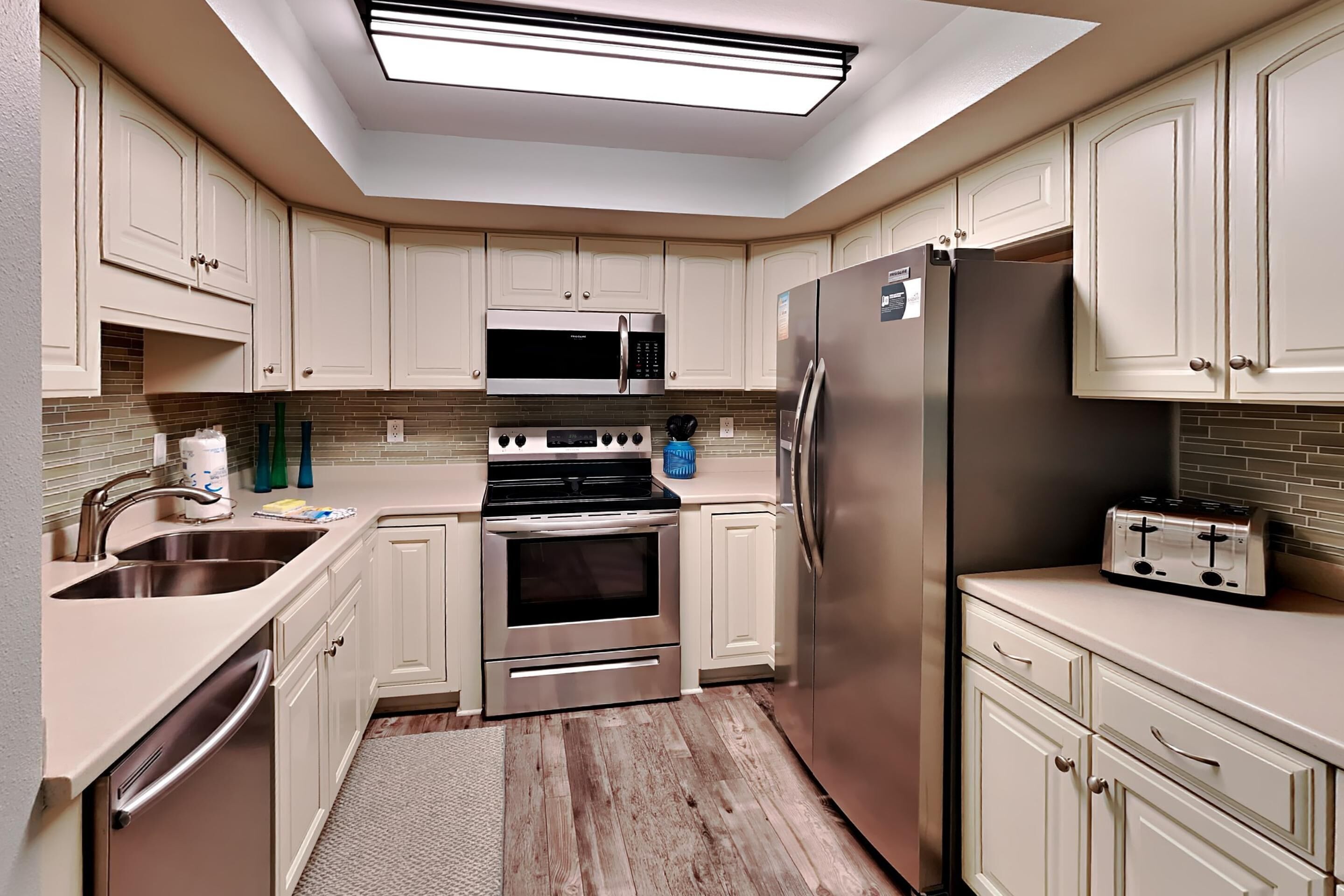 Una cocina moderna con armarios blancos, electrodomésticos de acero inoxidable y un tragaluz.