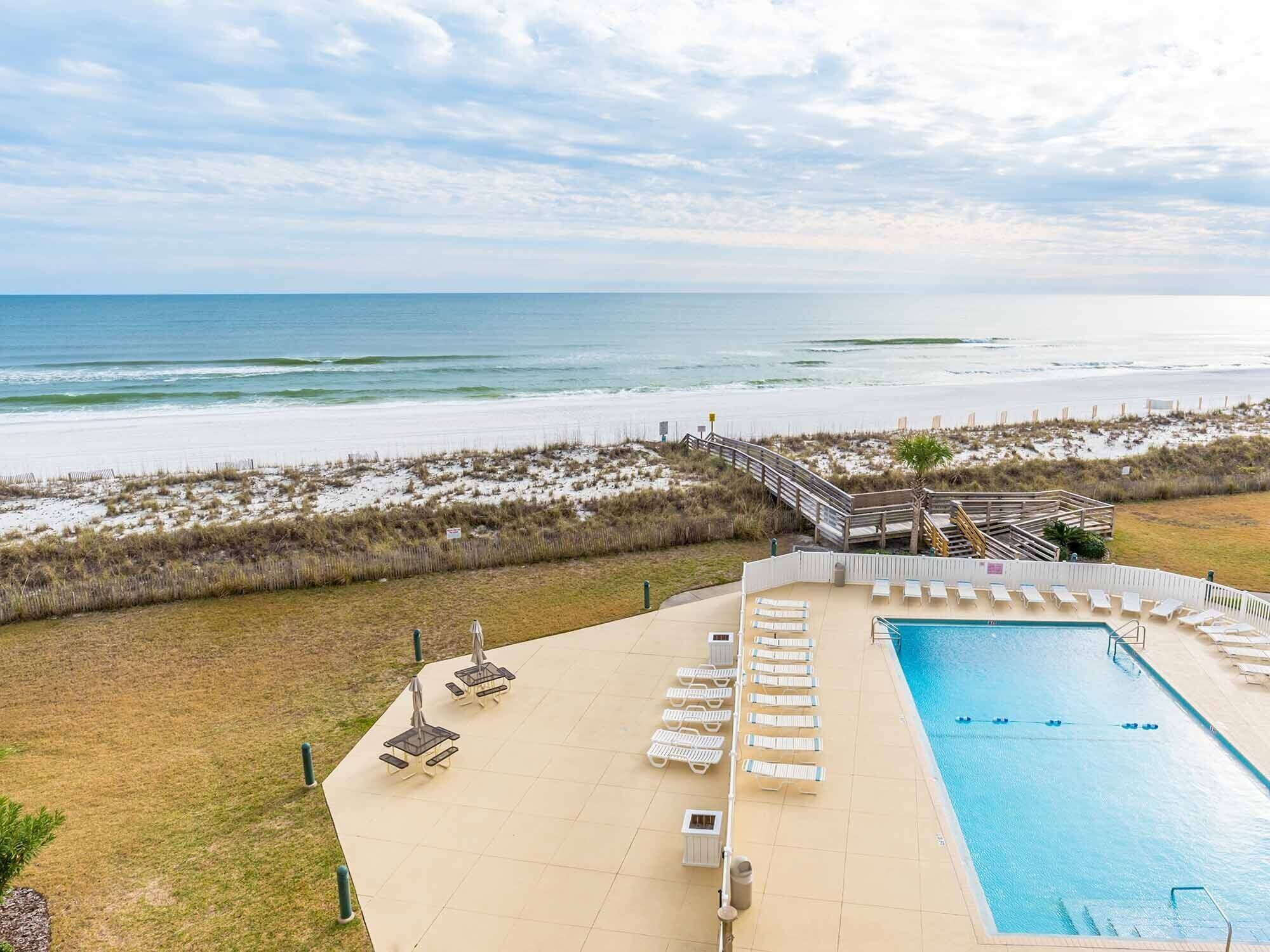 Zona de piscina con sillones de descanso y vista a la playa.