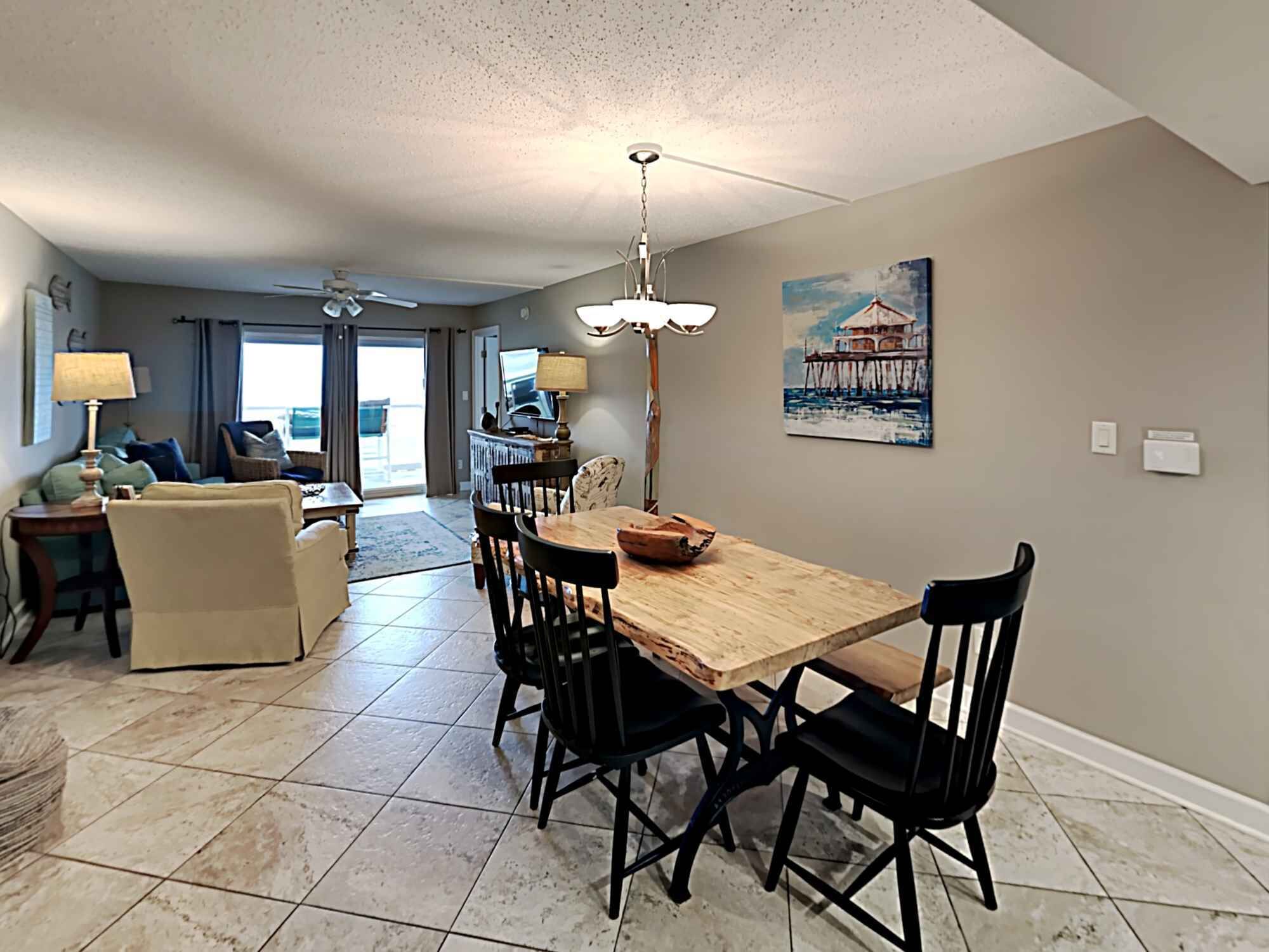 A spacious living area with a dining table, chairs, a sofa, and a ceiling fan.