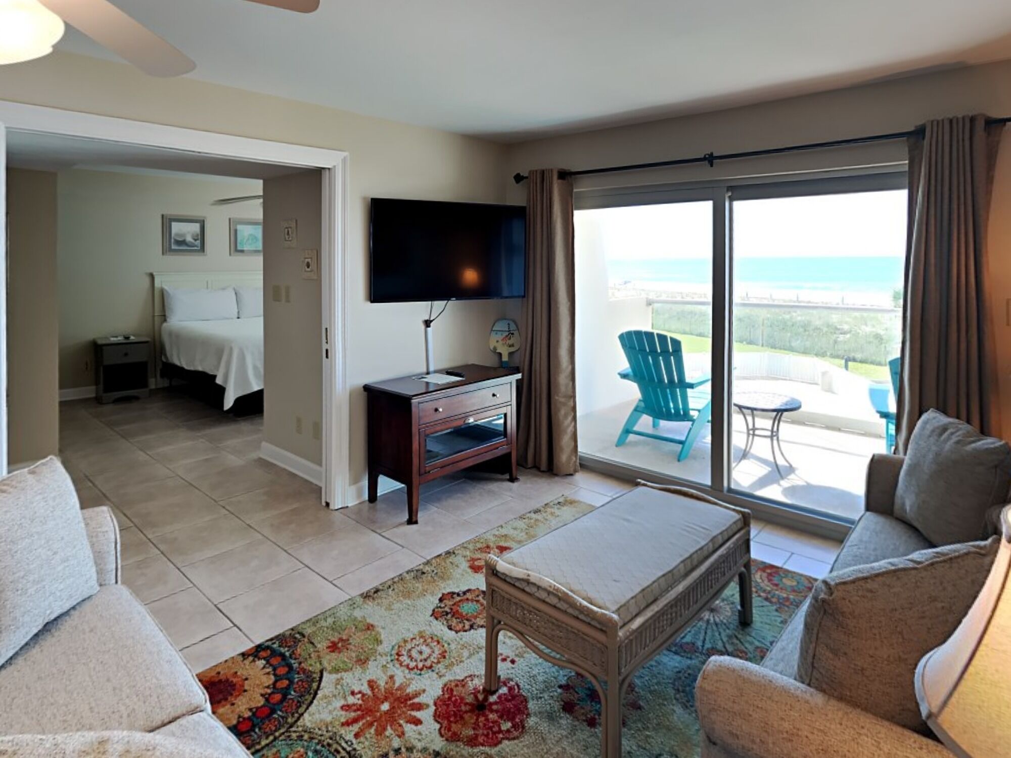 Quarto de hotel com cama, televisão, escrivaninha, cadeira, sofá e varanda com vista para o mar.