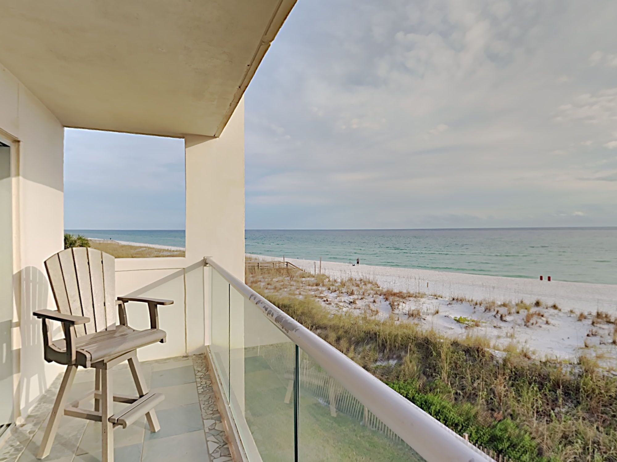 A balcony with a view of the beach and ocean.
