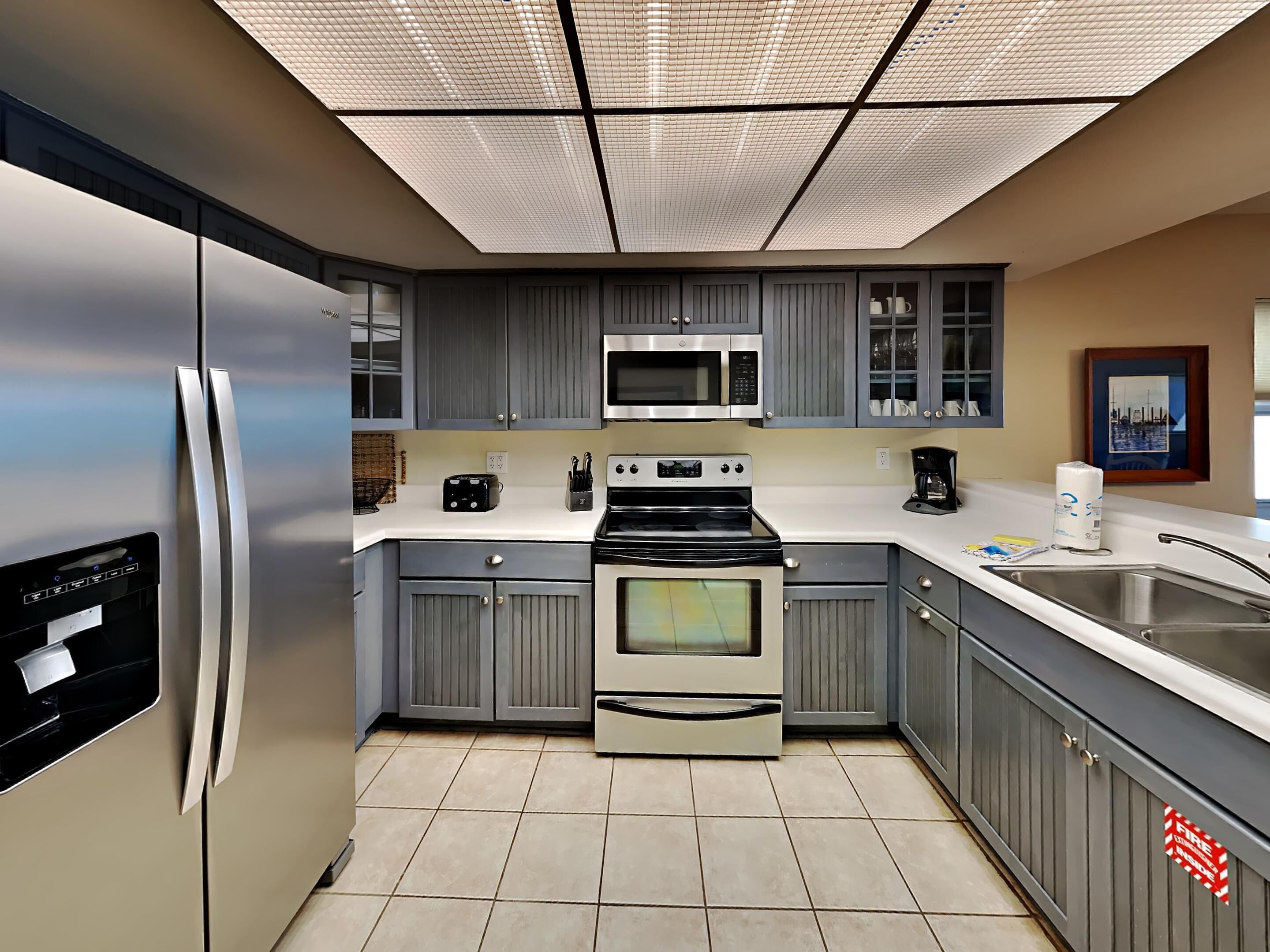 Una cocina moderna con gabinetes grises, electrodomésticos de acero inoxidable y piso de baldosas.