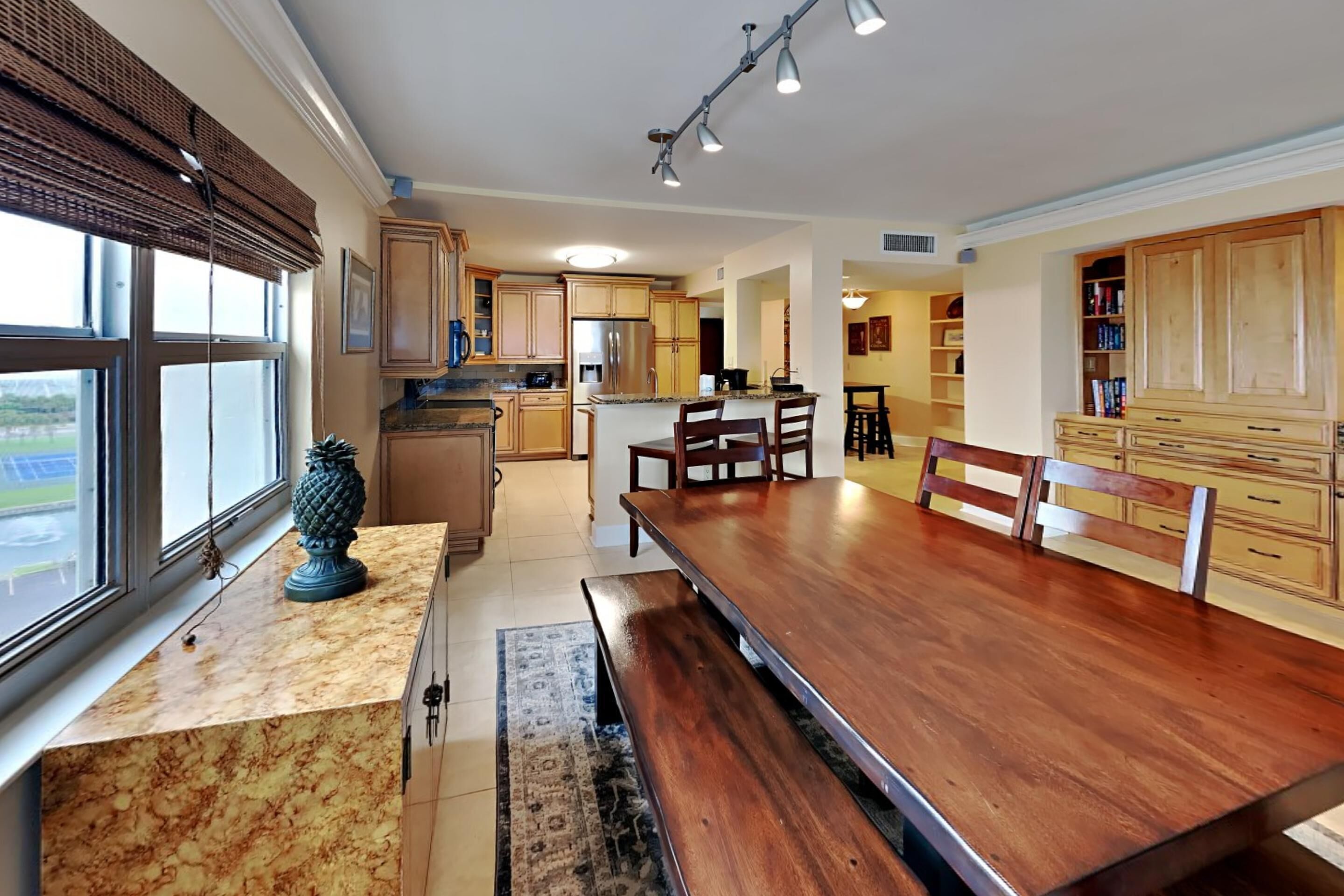 Una cocina amplia con armarios de madera, una mesa de comedor grande y vistas al exterior.