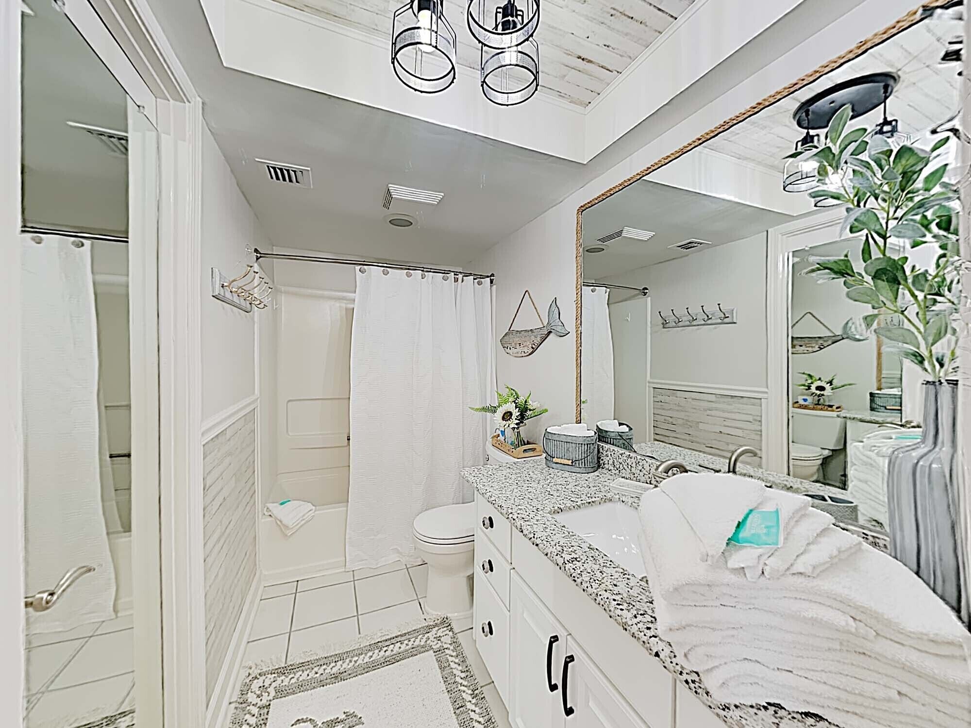 Un baño moderno con ducha, inodoro, lavabo y un espejo grande.