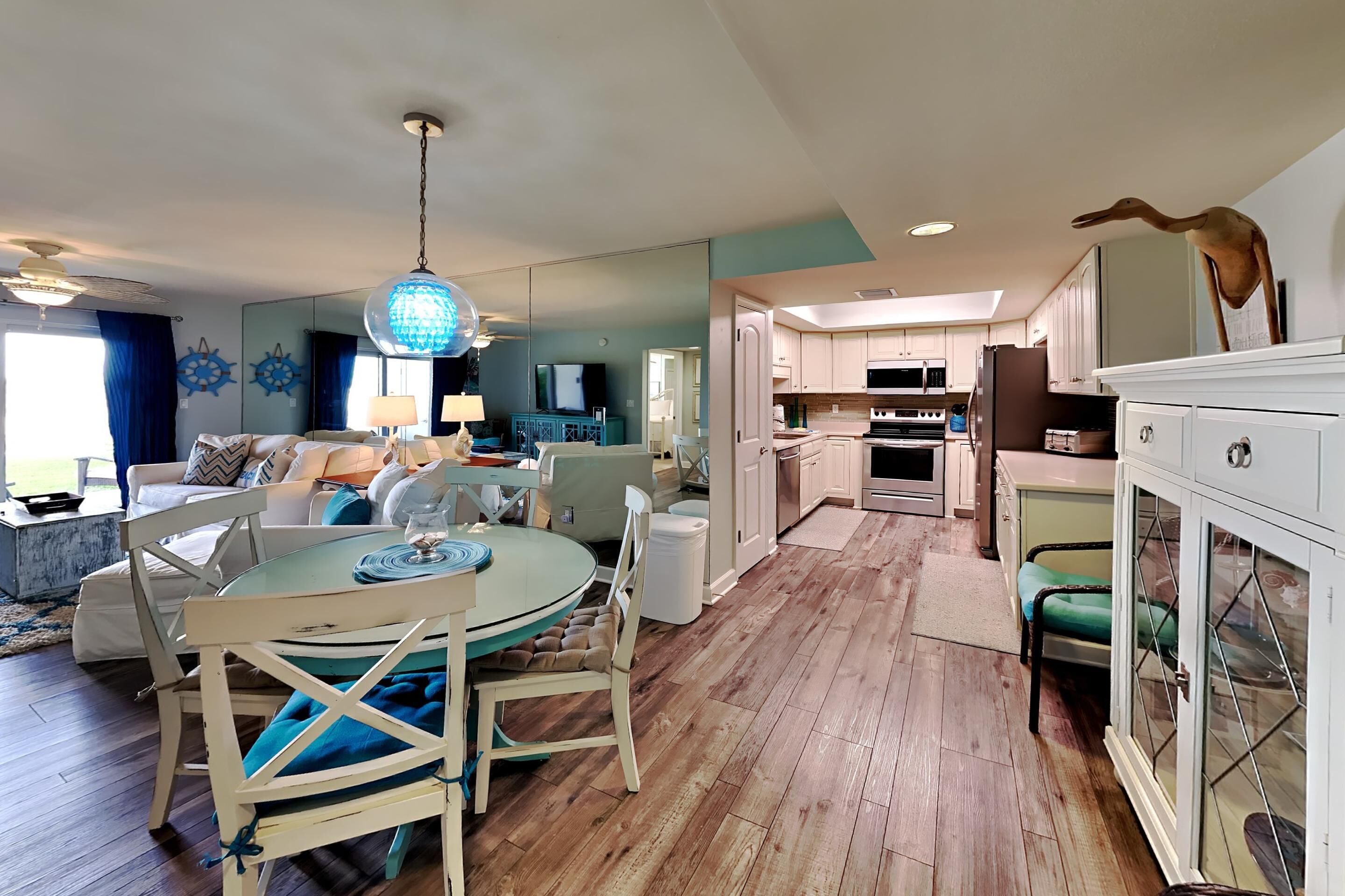A spacious living room with a round table, a sofa, and a dining area. A kitchen with modern appliances is visible in the background.