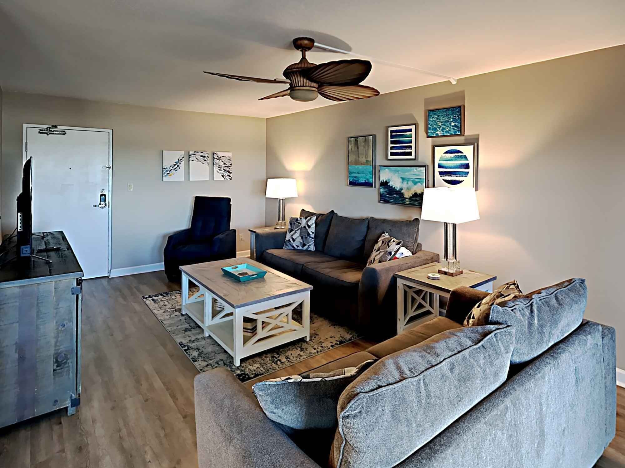 A living room with a ceiling fan, a sofa, a coffee table, and a TV.