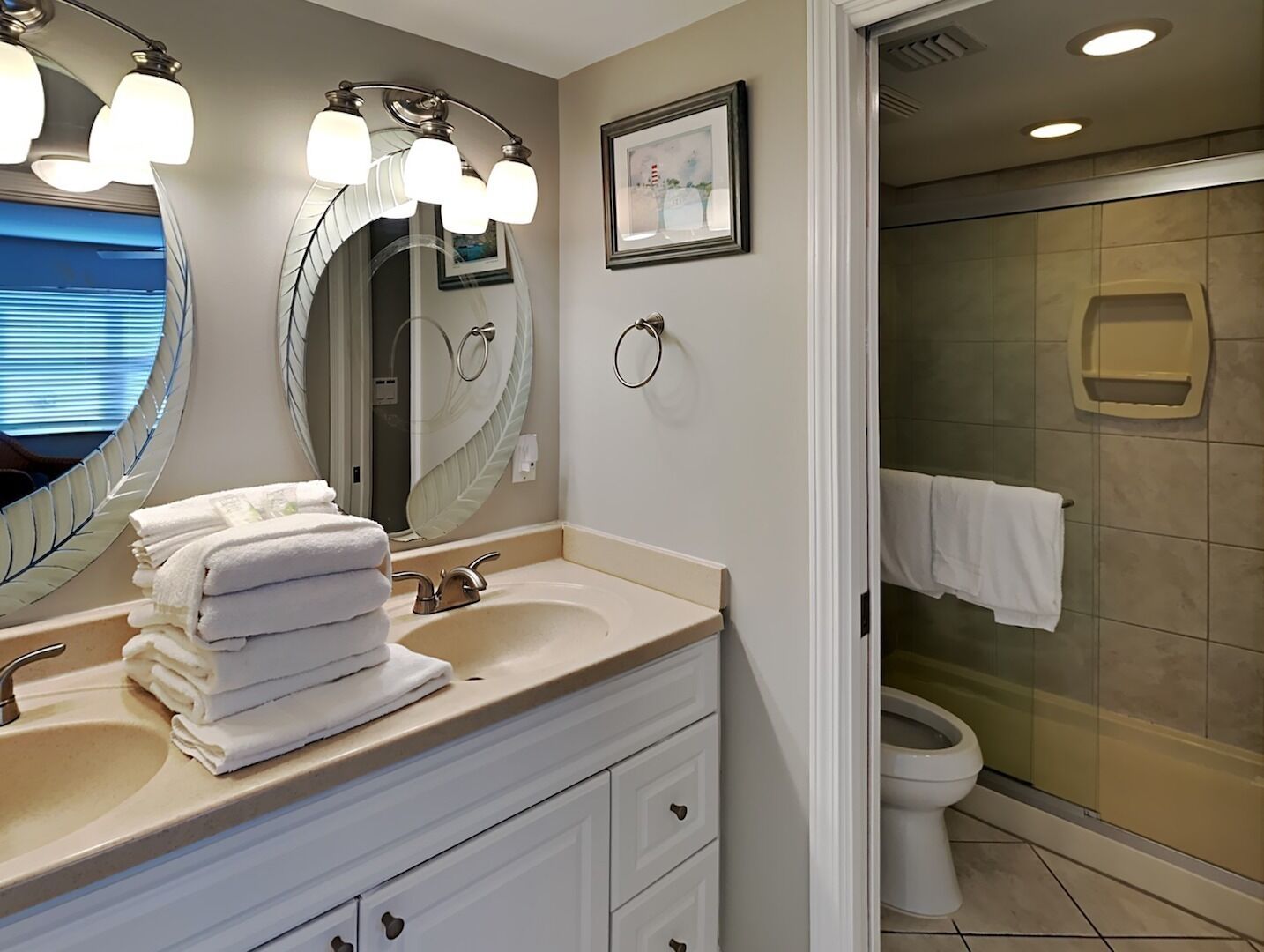 Une salle de bain avec deux lavabos, un grand miroir et un espace douche.