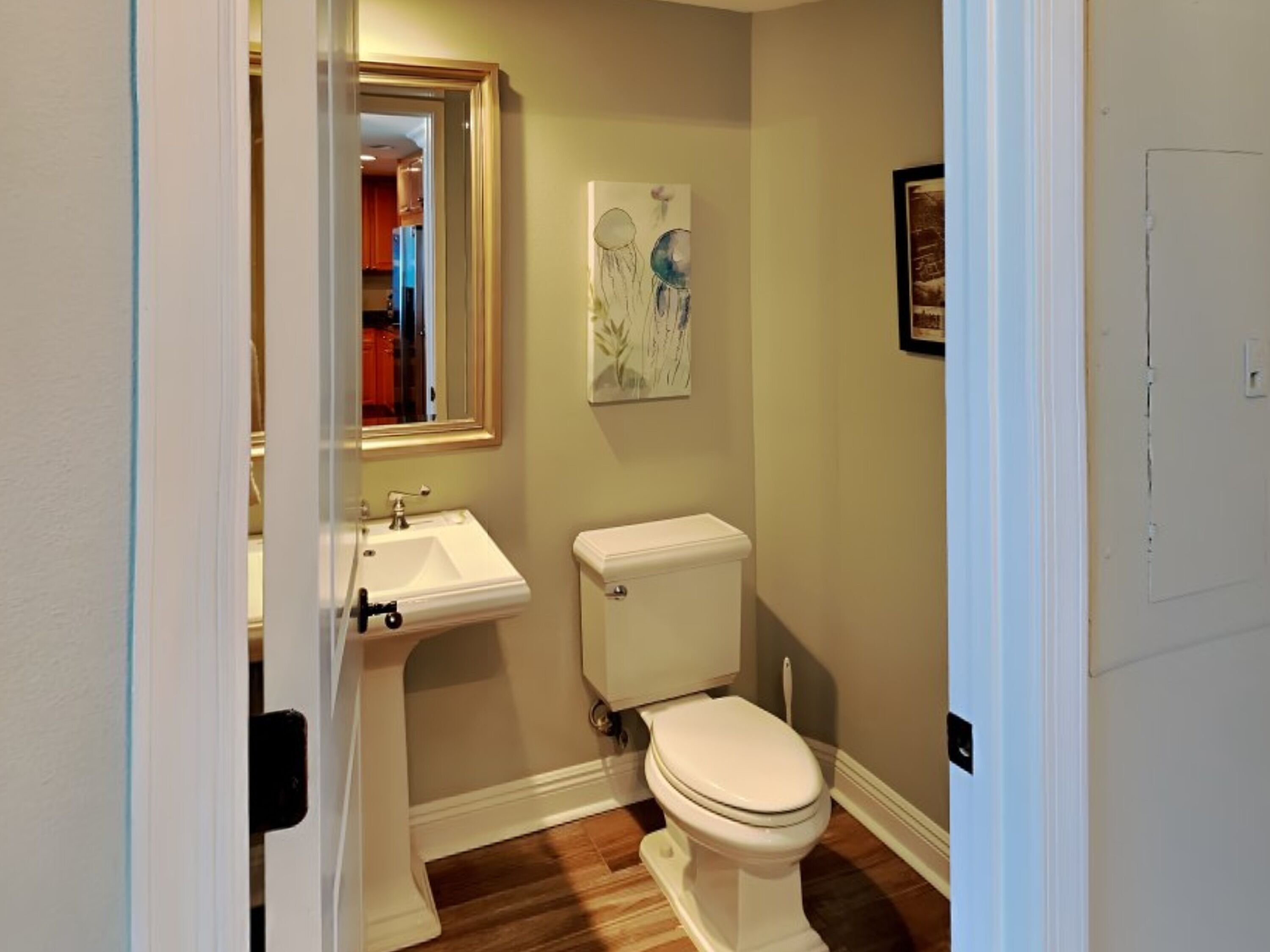 A compact bathroom with a white sink, toilet, and a mirror above the sink.