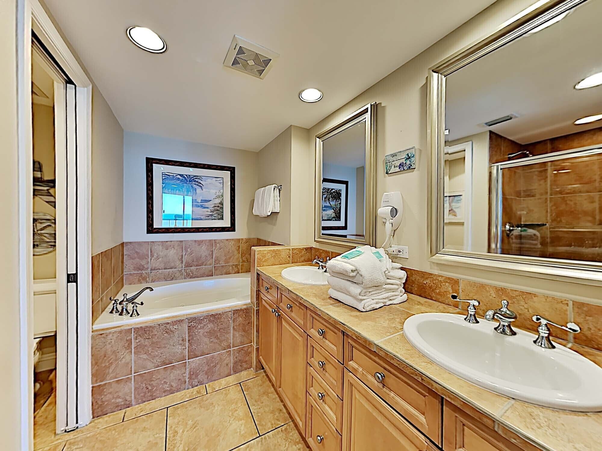 A modern bathroom with a large bathtub, a double sink vanity, and a large mirror.