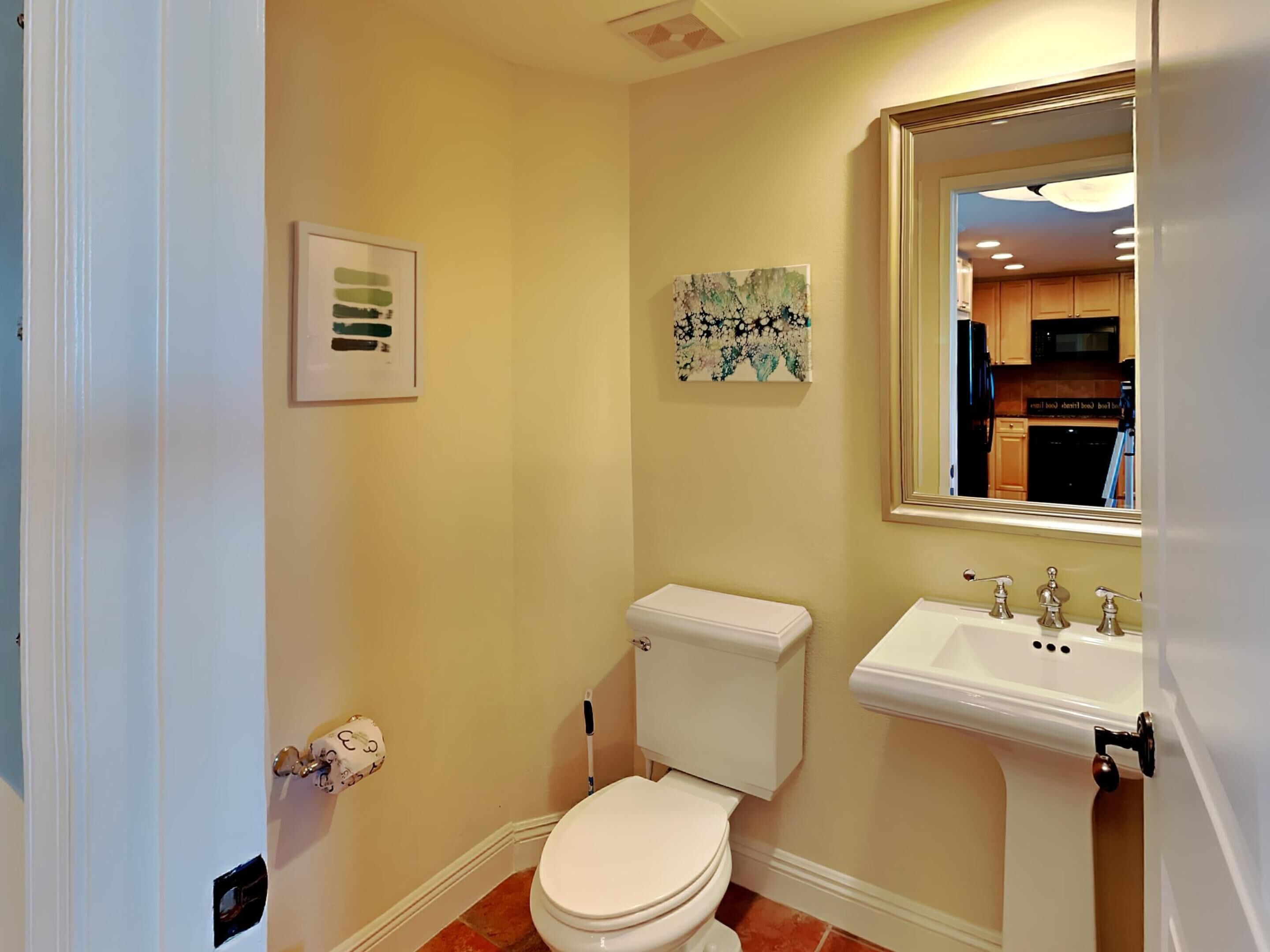 Une petite salle de bain comprenant des toilettes, un lavabo et deux œuvres d’art encadrées accrochées au mur.
