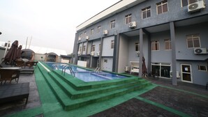 A rooftop pool area with a swimming pool, green steps, and outdoor seating. - Empresa Hotel & Spa (Lekki)