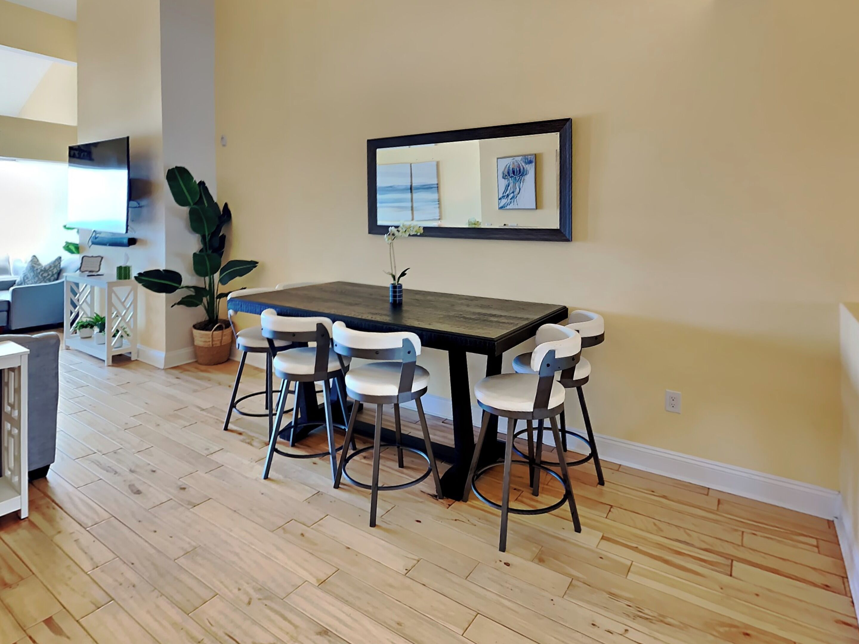 Un coin repas avec une table en bois et quatre chaises, une plante succulente et des œuvres d’art accrochées au mur.