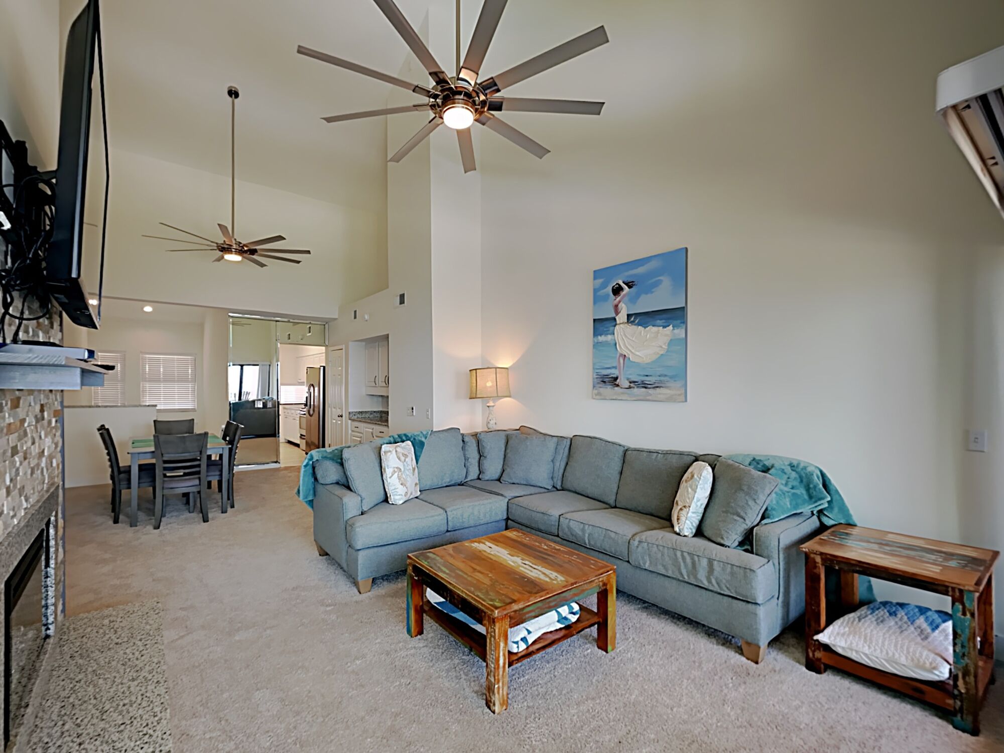 A spacious living room with a large sectional sofa, a wooden coffee table, and two ceiling fans.