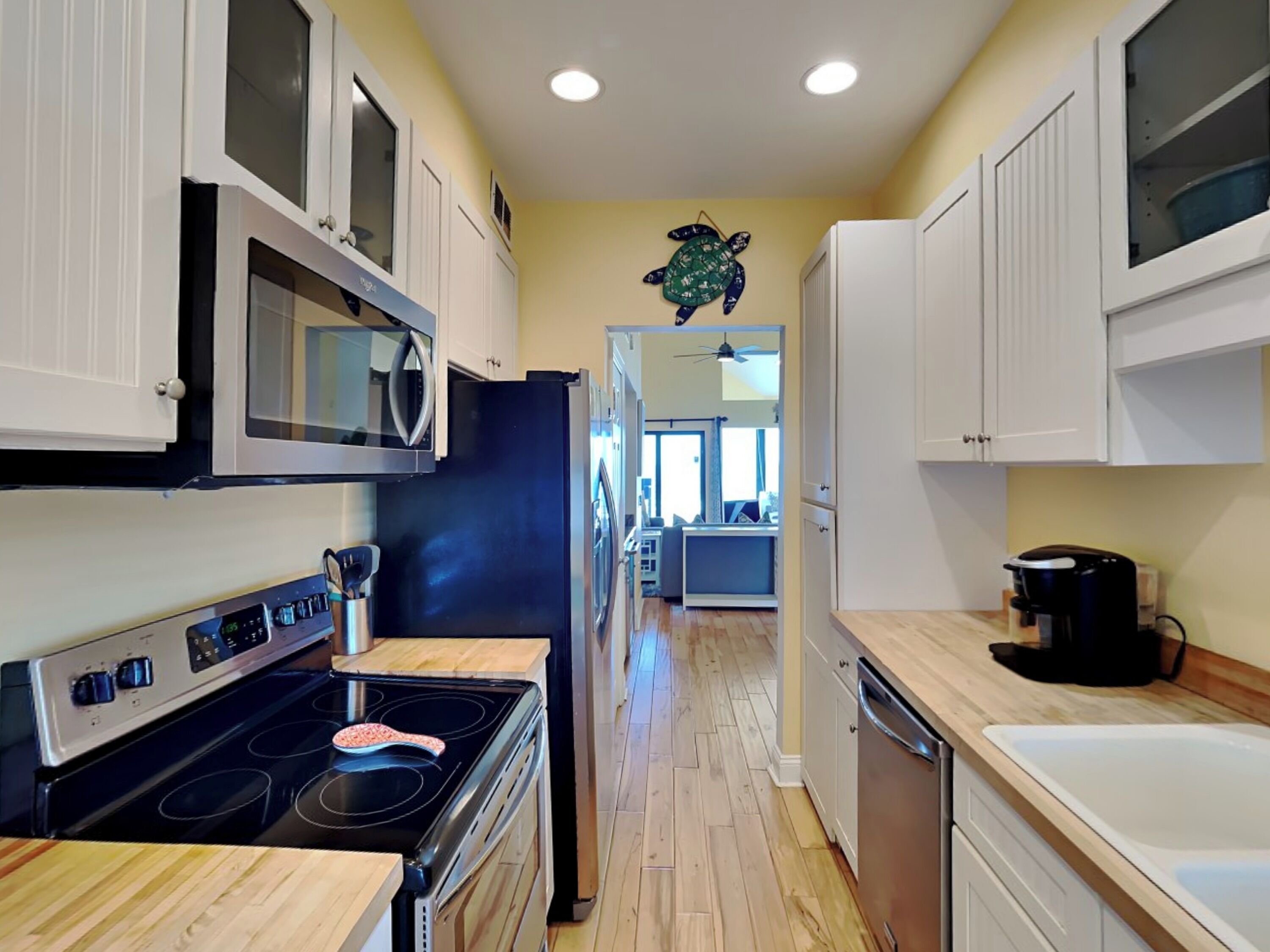 A modern kitchen with white cabinets, a black refrigerator, a microwave, a stove, and a sink.