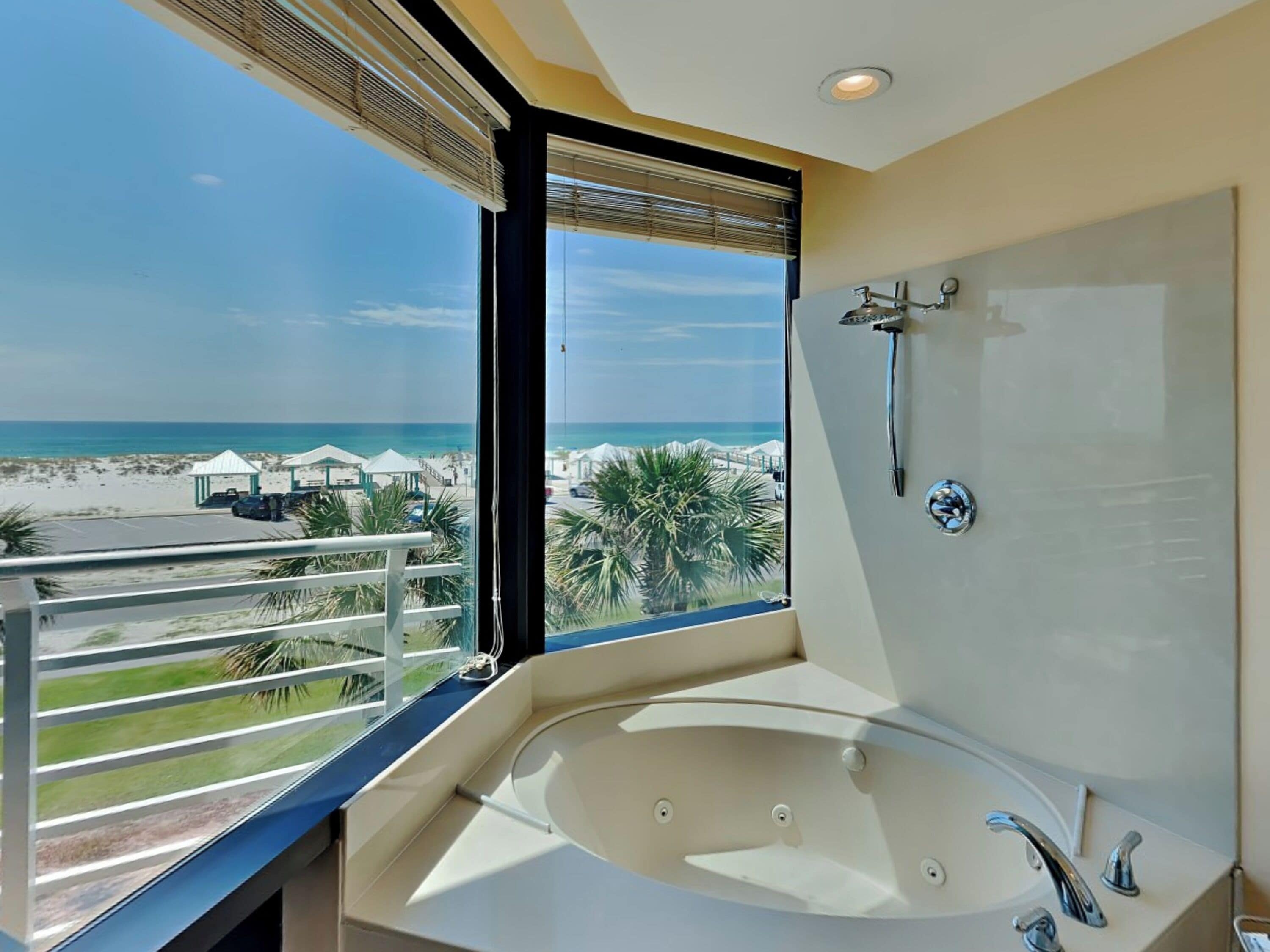 A bathroom with a large bathtub, a shower, and a view of the beach.