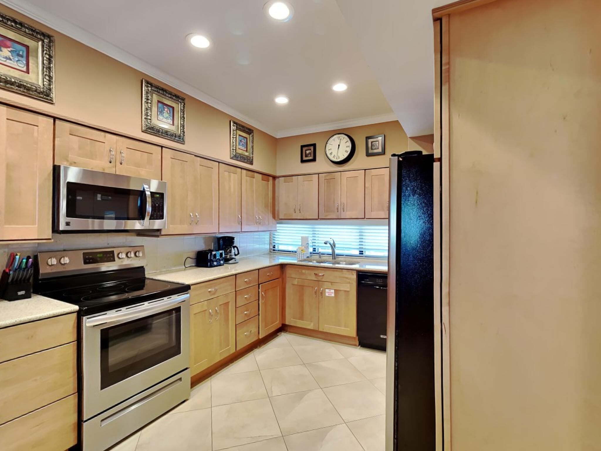 A kitchen with wooden cabinets, stainless steel appliances, a microwave, oven, and a refrigerator.