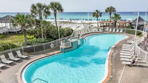 A pool with a curved design, surrounded by lounge chairs and a deck. - Pelican Beach by Southern Vacation Rentals (Destin)