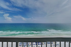 A beach view with a balcony overlooking the ocean.