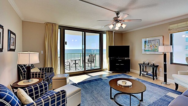 A hotel room with a balcony, a sofa set, a TV, and a coffee table. - Perdido Towers by Southern Vacation Rentals (Pensacola)