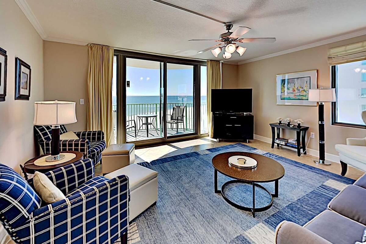 A hotel room with a balcony, a sofa set, a TV, and a coffee table.
