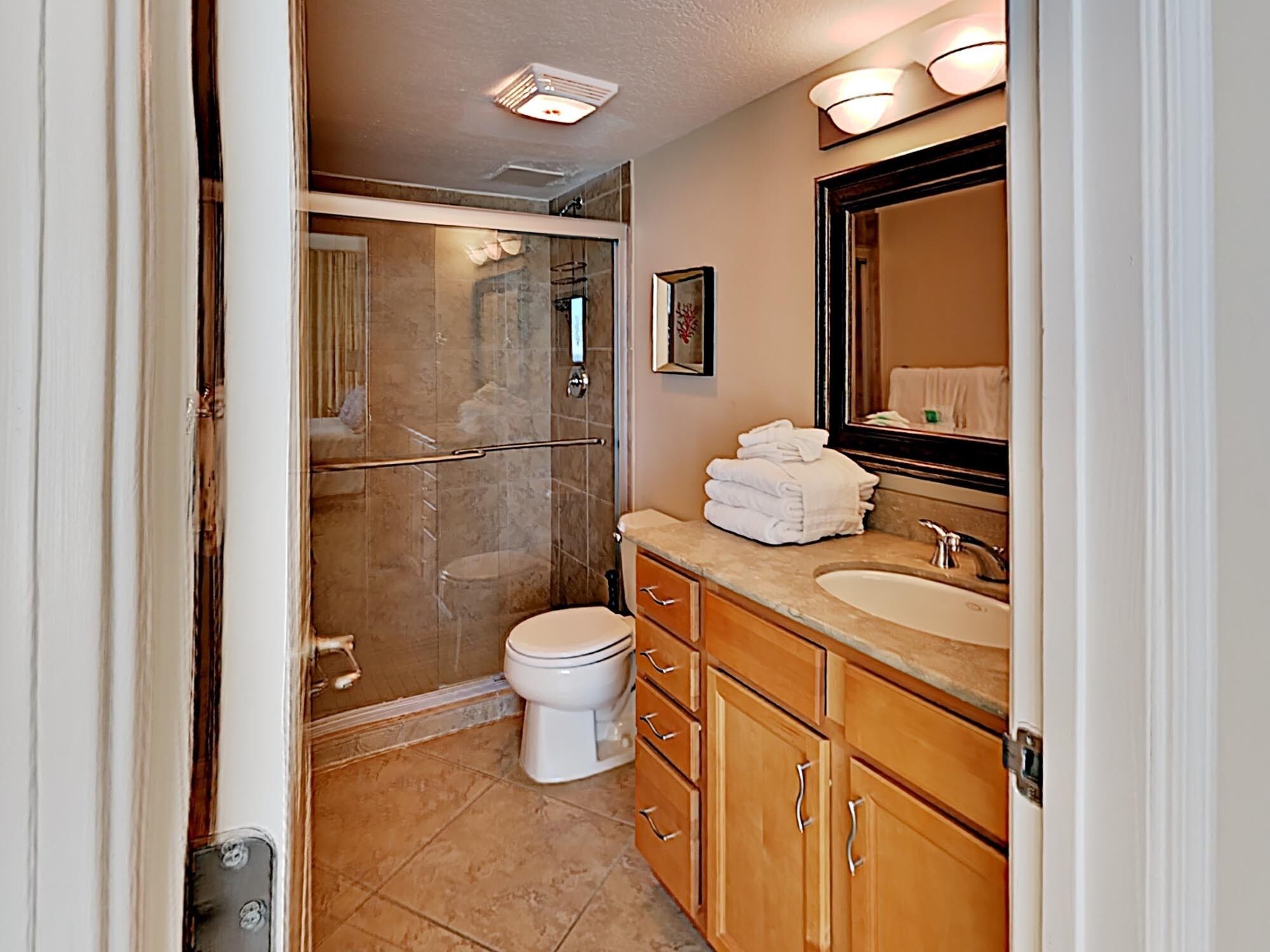A bathroom with a shower, toilet, sink, and vanity.