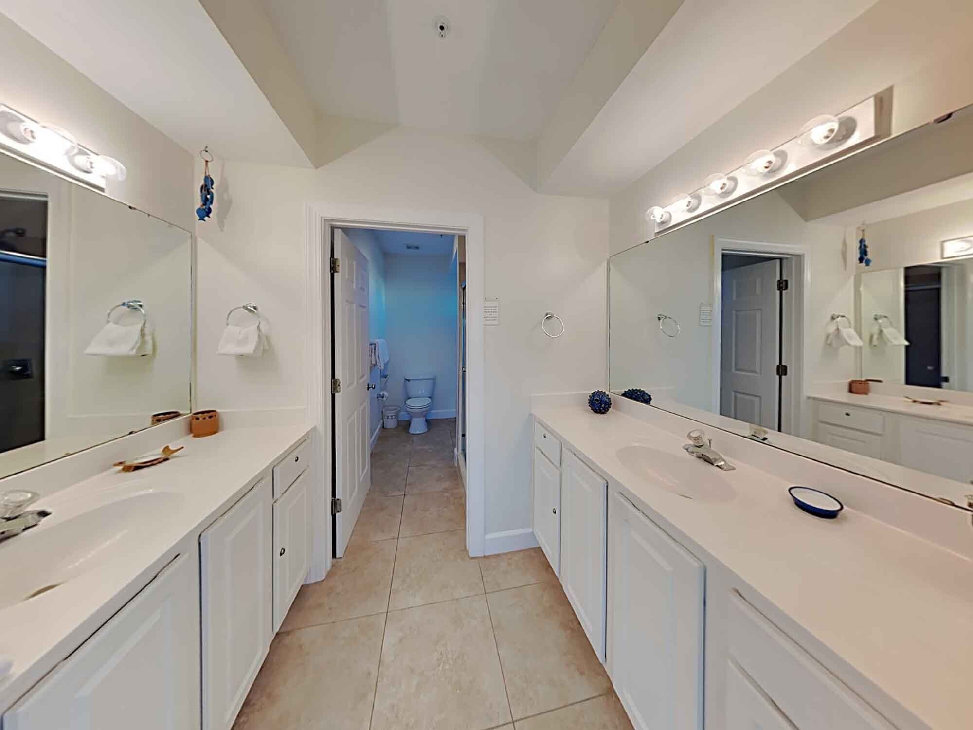 Un bagno moderno con due lavabi, ampi specchi e illuminazione a soffitto.