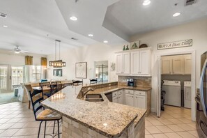 A spacious kitchen with granite countertops, white cabinetry, and a dining area with a large island.