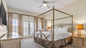 A four-poster bed with a canopy, a bedside table with a lamp, and a television on a stand. - Pavilion Palms by Southern Vacation Rentals (Miramar Beach)