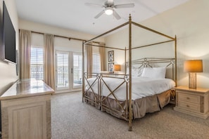 A four-poster bed with a canopy, a bedside table with a lamp, and a television on a stand.