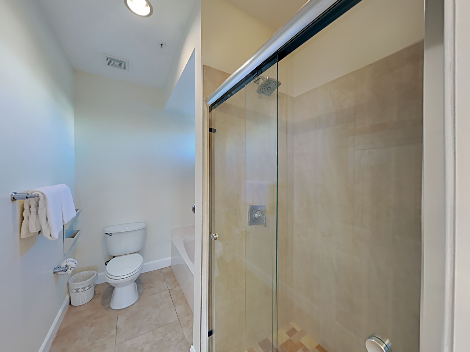 Une salle de bain avec une douche à parois de verre, des toilettes et un porte-serviettes.