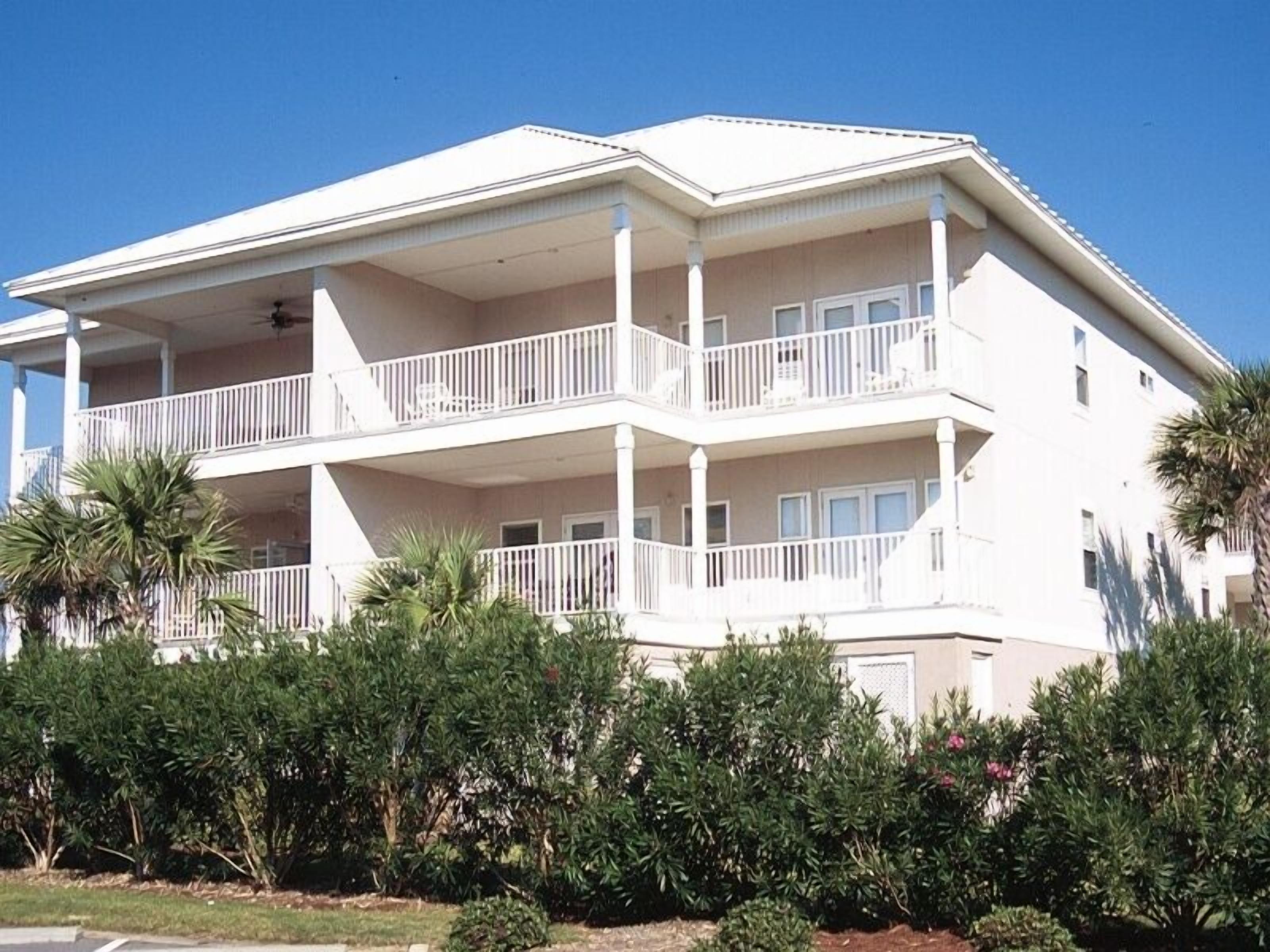 A multi-story hotel with balconies, surrounded by dense greenery.